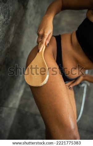Cropped view of blurred african american woman massaging wet skin with brush in shower