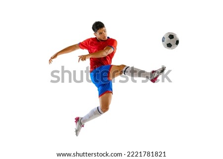 Portrait of young man in uniform, professional football player kicking ball in a jump isolated over white studio background. Concept of sport, team game, action, motion. Copy space for ad, poster Royalty-Free Stock Photo #2221781821