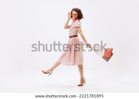 Portrait of beautiful woman eating bubblegum, walking with string bag isolated on white background. Shopping. Concept of beauty, retro style, fashion, elegance, 60s, 70s, family. Copy space for ad Royalty-Free Stock Photo #2221781895