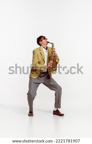 Portrait of young man in stylish yellow jacket playing saxophone isolated over white background. Jazz performer. Concept of live music, performance, retro style, creativity, artistic lifestyle Royalty-Free Stock Photo #2221781907