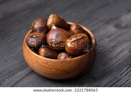cooked chestnuts in wooden bowl and wooden background floor Royalty-Free Stock Photo #2221788063