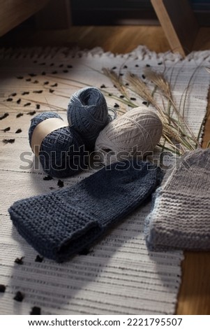 Knitted socks, ball of yarn on a wool carpet. Home cozy rustic interior. The concept of knitting, needlework, hobbies.
