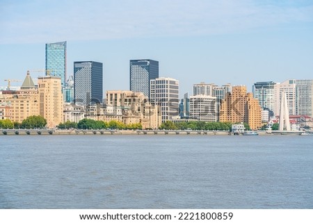 shanghai skyline in the morning, showing the Huangpu river with passing cargo ships, financial district buildings and cloudy sky background