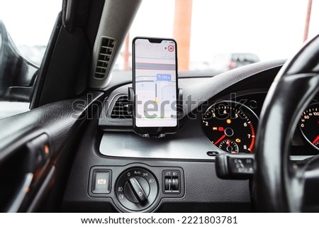 Smartphone with navigation route on screen mounted on phone holder at car dashboard Royalty-Free Stock Photo #2221803781