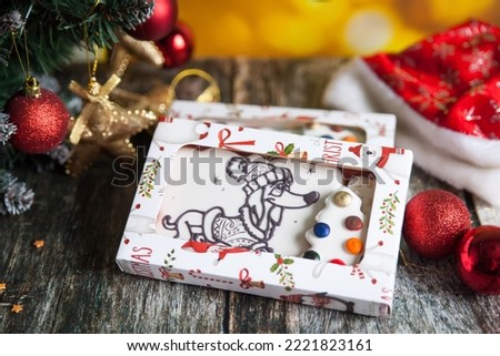 Gingerbread cookies for Christmas presents with palette to color them. Gingerbread with a picture of a puppy. Present kit. Year of the dog. Christmas fir branch and decorations on background