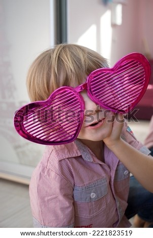 portrait of cute child boy in huge funny heart shaped glasses. Birthday, Valentine's Day, Mother's Day. Declaration of love with humor