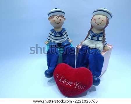 a character statue of a couple with a red heart pillow that reads I love you, can be used as a background for Valentine's Day greetings