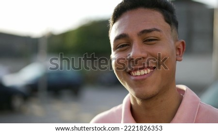 Portrait of a happy hispanic young man smiling at camera standing outdoor. One casual South American male person. Brazilian guy Royalty-Free Stock Photo #2221826353