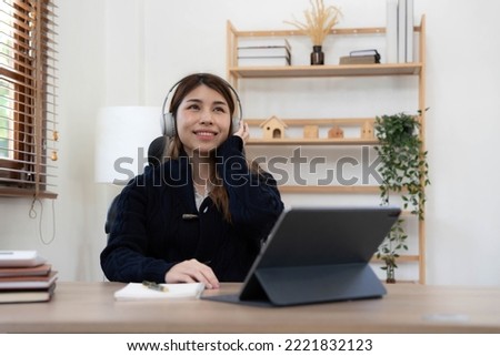 smiling girl relaxing at home She is listening to music using her laptop and wearing white headphones.