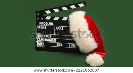 Movie clapper with Santa Claus hat on green background