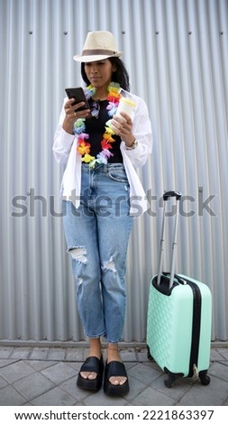 young woman with suitcase searching location on mobile