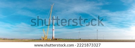 Building and assembling a construction windturbine by Crawler Track Crane - machinery. Farmland with construction work at the windfarm, Wörrstadt, Germany. Energy crisis concept, Panoramic web banner