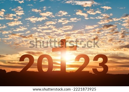 Silhouette of Christian cross with 2023 years at sunset background. Concept of Christians new year 2023 Royalty-Free Stock Photo #2221873925