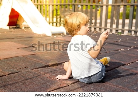 Cute child, blond boy, playing on playground on a cloudy day, summertime