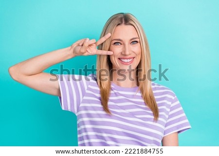 Photo of good mood optimistic nice woman with straight hairstyle wear striped t-shirt showing v-sign isolated on blue color background