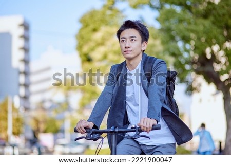 Young Japanese man in a jacket riding a bicycle Royalty-Free Stock Photo #2221900047