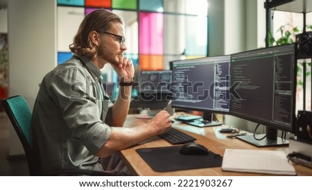 Male Programmer Coding on Desktop Computer With Two Monitors Set Up in Creative Office. Caucasian Man Using Artificial Intelligence to Create Innovative Software for Succesful Start-up Company. Royalty-Free Stock Photo #2221903267