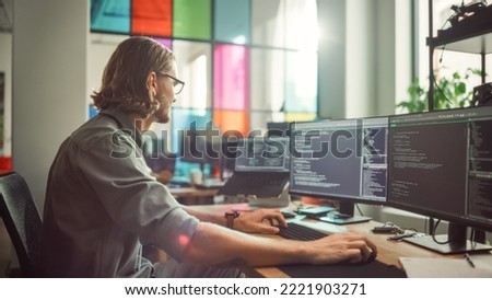 Professional Male Programmer Writing Code on Desktop Computer With Multiple Displays in Stylish Office. Caucasian Man Does Data Scraping For Artificial Intelligence Innovative Start-Up. Royalty-Free Stock Photo #2221903271