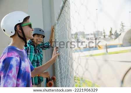 Teenage boys at fence of skateboard park