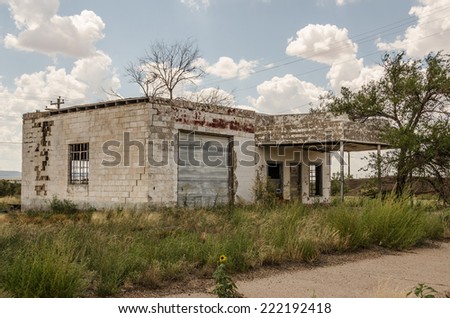 Neglected and abandoned former gas station and repair shop with a large crack in the building and lots of weeds in the yard on Route 66 Royalty-Free Stock Photo #222192418