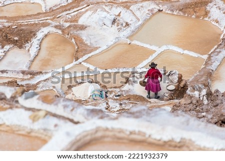 Woman extracting salt at Maras Peru. Woman on a colorful dress extracting salt at the salt terraces, called Maras, near Cusco, Peru Royalty-Free Stock Photo #2221932379