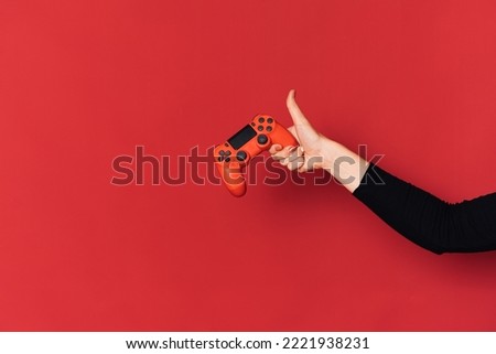 Gamepad in lady hand against red background.