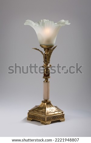 Antique table lamp with bronze details and a lampshade on a light gray background