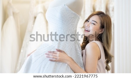 Beautiful asian woman in wedding dress, wedding rings, wedding bouquet. Bride.Young fashion model with perfect skin and make up, beige background, curly hair and flowers. 