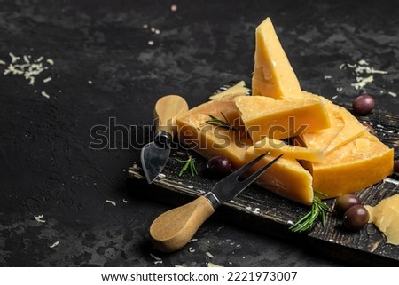 Parmesan cheese on a wooden board, Hard cheese on a dark background. top view.