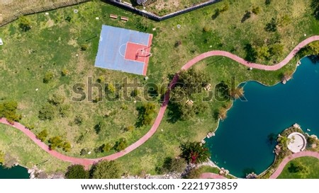 Aerial drone view of a basketball court and a lake in the middle of a park with no people. aerial shot