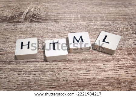 Lettered plastic tiles on wooden board displaying the acronym HTML (HyperText Markup Language).