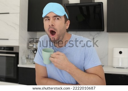Sleepy looking man holding coffee cup in the kitchen 