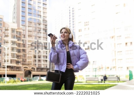 caucasian woman 40 years old in headphones speaks on a mobile phone hands-free outside