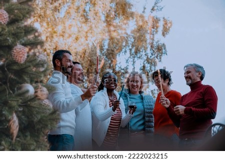 Diverse Group of People celebrating Christmas Holiday together with sparklers outside in garden party. Copy space