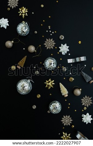Aesthetic creative arrangement of colourful golden, beige Christmas balls and toys on black background. Flat lay, top view