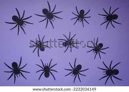 Black spiders on a purple background, color background and silhouettes of spiders, festive scary background, frightening decoration for Halloween, paper crafts gifts, material for needlework