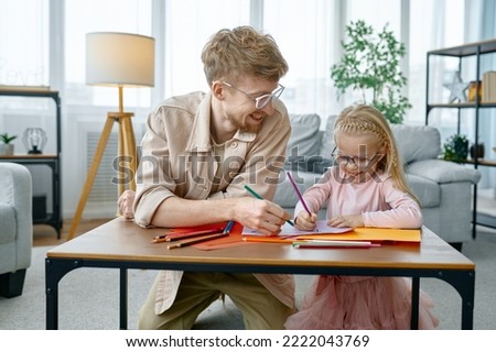 Happy father and daughter drawing sitting at desk table