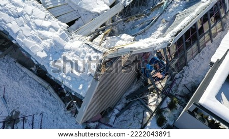 Roof collapsed under the weight of snow. Aerial view of damaged falling roof inside a publica city area. Large collapsed condominium or industrial company. View from above with a drone Royalty-Free Stock Photo #2222043891