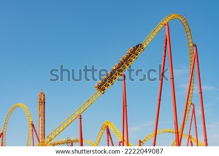 Yellow and red roller coaster with upturning trolleys on a turn and a loop Royalty-Free Stock Photo #2222049087