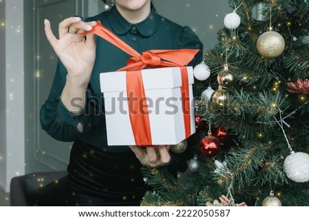 Time gifts. Happy Woman Holding a Christmas Presents in her Hands. Pretty woman giving or receiving presents at the Christmas tree