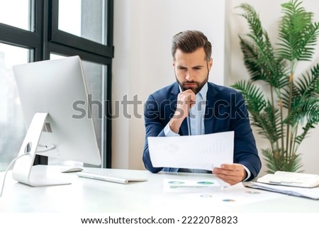 Focused successful clever caucasian business man in a suit, company ceo, financial director, sits at a work desk in the office, works with documents, analyzes and develops business financial strategy Royalty-Free Stock Photo #2222078823