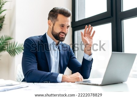 Positive caucasian businessman, executive manager, looking at laptop screen and talking by video conference, having online virtual meeting with colleagues, smiling. Online video communication
