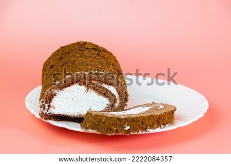 Chocolate roll with white cream on a pink background. The concept of women's sweets.