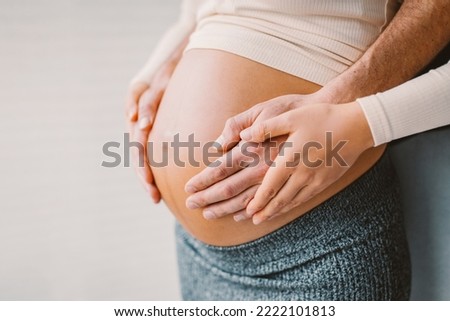 Pregnancy photo man and woman holding pregnant bump expecting baby. Happy family hands on stomach closeup. Couple in love. Royalty-Free Stock Photo #2222101813