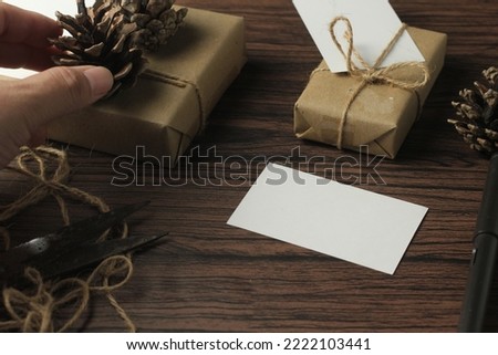 male hands wrapping new year gifts and writing cards On a brown wooden table.
