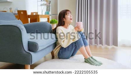 happy asian woman holding mug drink beverage feeling cozy and warm enjoying sitting in living room at home during winter Royalty-Free Stock Photo #2222105535