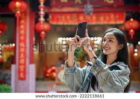 Close up view of young woman taking a photo with smartphone while traveling in Asian traditional temple
