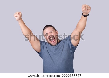 A man screams and shouts in elation. Overjoyed man celebrating victory. Isolated on a gray background. Royalty-Free Stock Photo #2222138897