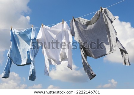Clean clothes hanging on washing line against sky. Drying laundry Royalty-Free Stock Photo #2222146781