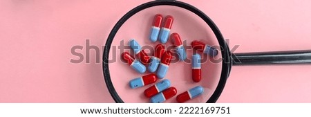 Magnifier with medical pills and red stethoscope. Search and selection of medicines for the treatment of diseases concept